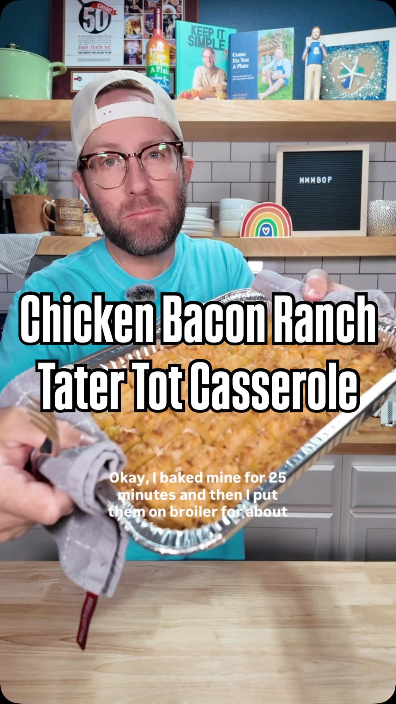 The cover image shows a man holding a foil pan filled with a Tater Tot casserole. Large text overlays the image with the dish's name. The man has glasses and a white cap. The background shows a kitchen setting with shelves, cookbooks, and decorative items.