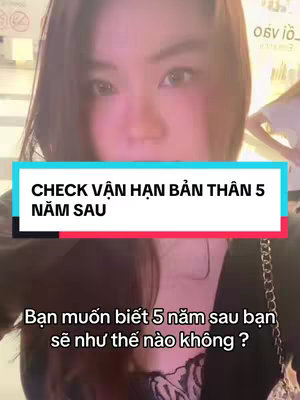 A selfie-style image featuring a woman looking directly at the camera. She has dark hair and a fairly neutral expression. The background appears blurred, but there's a suggestion of a light-colored interior. A rectangular banner with white text on top of a blue and red background covers part of the image.