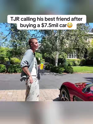 A man in casual wear stands on a brick driveway next to a red sports car, talking on his phone. The background consists of lush greenery and a large house. Above the scene, white text on a black banner reads "TJR calling his best friend after buying a $7.5mil car 😳".