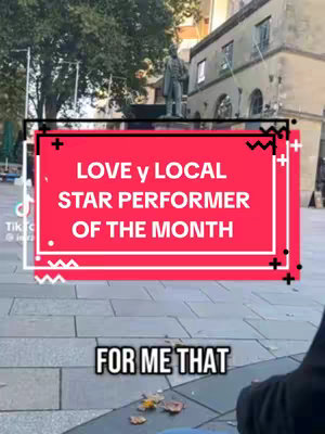 The cover image displays a street scene with a statue in the background. A red rectangular overlay with white text is placed over the image, with the text centered and in all caps: LOVE y LOCAL STAR PERFORMER OF THE MONTH.  Below this, the text FOR ME THAT is visible in a white box.