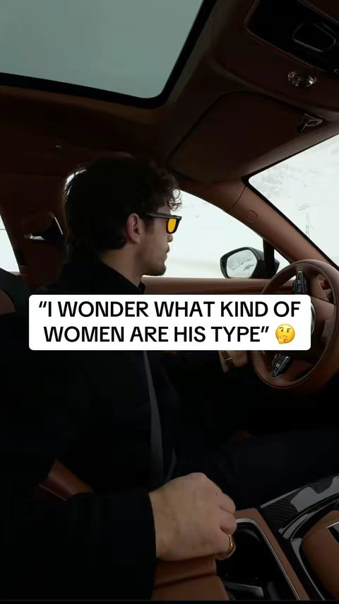 A man wearing sunglasses is seated in the driver's seat of a luxury car. Overlay text in a white banner asks, "I wonder what kind of women are his type." The overall composition is an interior shot emphasizing the driver and vehicle's interior.
