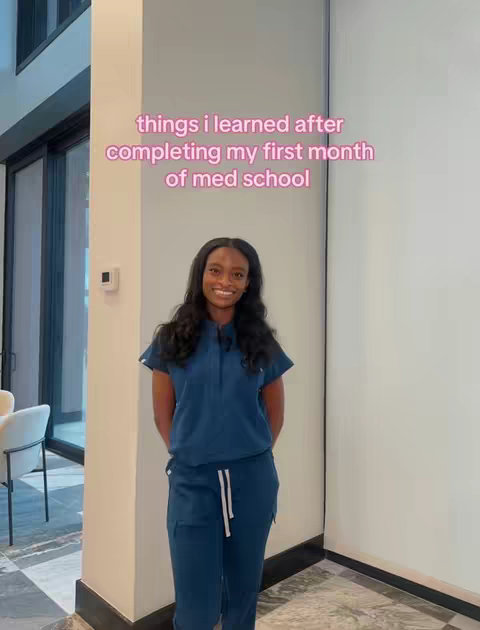 A woman in blue scrubs stands in front of a neutral-colored wall in a well-lit space. Text overlay reads 'things i learned after completing my first month of med school'.