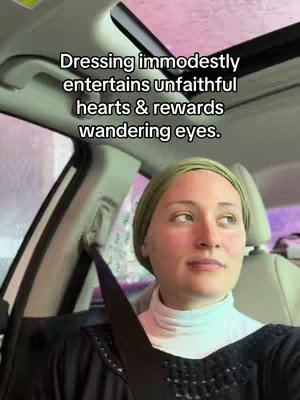 A woman is seated in a car, angled towards the right. She wears a light green headscarf and a white turtleneck sweater. Black text overlays the image. The setting appears to be outdoors, with a window and a hint of a hazy sky.