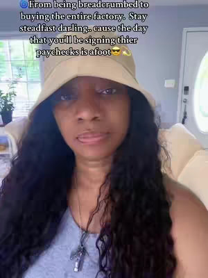 A woman with long, wavy black hair is centered in the frame, wearing a light beige bucket hat and a gray tank top. She has a neutral expression and a light complexion. Text overlayed on the image forms a motivational quote arranged with a few emojis, and the background has a partially visible indoor setting.