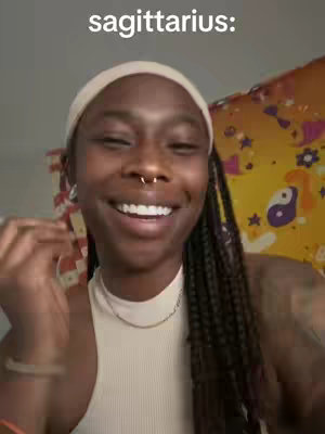 The cover image features a smiling woman with a headband and nose ring, positioned in front of a colorful background with a yin-yang symbol. The text overlay reads "sagittarius:" in a bold, white font.