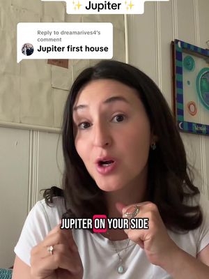 A selfie-style video cover image featuring a woman with brown hair and fair skin, looking directly at the camera with an open mouth as if she is speaking. Text overlayed on the bottom of image on a black background, reads: "JUPITER ON YOUR SIDE". In the background is a white wall with a decor on the right side, and the head of the woman is in front of that background, creating a contrast.
