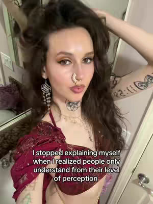 A selfie-style shot featuring a woman with long brown hair, wearing a red halter top, and adorned with jewelry. Text overlayed on the bottom of the image reads, "I stopped explaining myself when I realized people only understand from their level of perception."