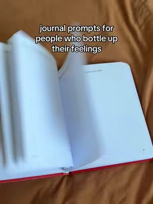 An open journal with white pages is shown on a tan surface, presumably a bedsheet or blanket. Overlaid on top is white text that describes the type of prompts.