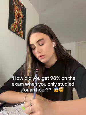 A young woman sits at a desk, writing in a notebook. She's wearing a black top and has long hair with highlights. Text overlay adds a question, implying a study tip or tip about getting a high exam grade quickly.