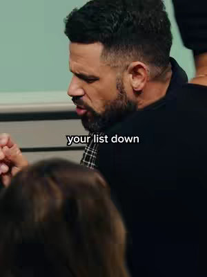 A man with dark hair and a beard is featured in a close-up shot. The man's gaze is downward, and his expression suggests a moment of thought or intensity. Below him, in a light-colored font, the text "your list down" appears.