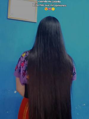 The cover image shows back of a person with very long, shiny black hair against a bright blue wall. The person is wearing a purple shirt with colorful patterns, and a red skirt. There is a small frame hanging on the wall.