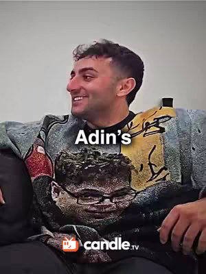 The cover image features a man looking to the side with a slight smile. He is wearing a crew neck sweater with a large image on the front of a man wearing glasses and looking forward. Above the sweater is the word "Adin's". There is a logo of candle.tv at the lower center. The background is light in color.