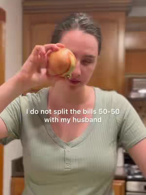 A woman is shown indoors, holding an onion with one eye partially obscured. Her expression is neutral. Text overlayed reads "I do not split the bills 50-50 with my husband."