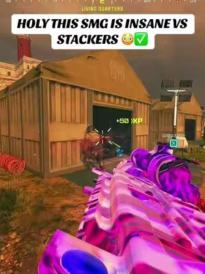 The cover image shows a first-person view of a video game screen, likely Call of Duty: Warzone. The player is aiming a custom SMG with a vibrant pink and purple skin at a building entrance where an enemy is visible. The image has a text overlay with the text "HOLY THIS SMG IS INSANE VS STACKERS" and a checkmark, indicating approval or highlight.  The scene is set in a brown and tan-colored environment. The composition is from a first-person viewpoint, presenting the game's action.