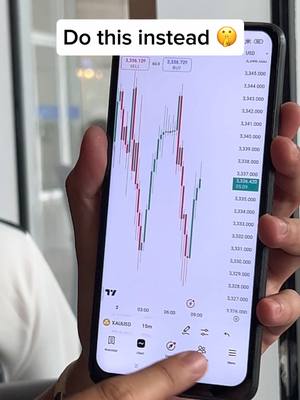 A person using a smartphone displaying a trading platform with a stock chart. The phone is held in a person's hand. The screen shows green and red lines depicting stock prices, with a "Do this instead" overlay.