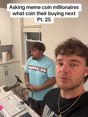 Two men are in a room. The primary focus is on the man in the foreground who is holding the camera up and talking.