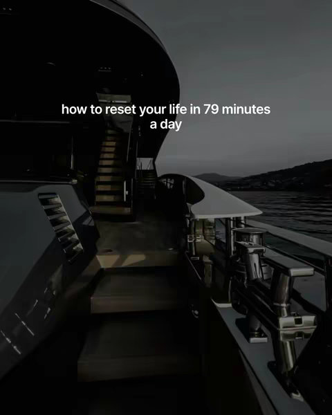 A view from the deck of a luxury yacht, showcasing the dark color scheme of the vessel and the calm sea in the background. Text overlayed on image reads "how to reset your life in 79 minutes a day."