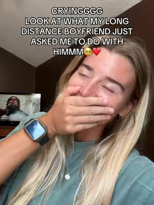 The cover image shows a woman in a teal shirt, covering her mouth with her hand while crying and smiling. The image has overlaid text in the upper portion suggesting the content will be about her long-distance boyfriend. A television with a man on the screen is visible in the bottom left.