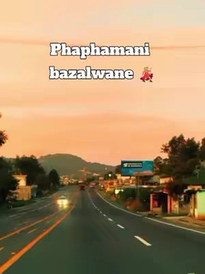 A road stretches into the distance, flanked by trees and buildings under a warm-toned sky. Text overlayed across the top of the image.