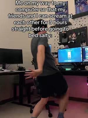 A person in a casual outfit appears to be mid-dance or in an excited pose. They are set against a backdrop of a gaming setup with multiple monitors, decorative elements on a wall shelf, and ambient lighting.