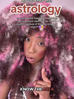 A selfie-style video cover image featuring a woman with curly hair dyed with pink highlights, a nose ring, and dramatic makeup. Text overlays announce the topic, 'astrology' and 'KNOW THE AREA.' The woman points her finger directly at her audience, suggesting direct communication.