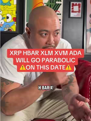 The cover image features a bald man with light skin, wearing a white t-shirt, sitting on a red leather chair. He is gesturing with his hands while looking slightly off-camera. Overlay text in red states "XRP HBAR XLM XVM ADA WILL GO PARABOLIC ⚠ON THIS DATE!⚠". The background includes artwork and a dark wall.