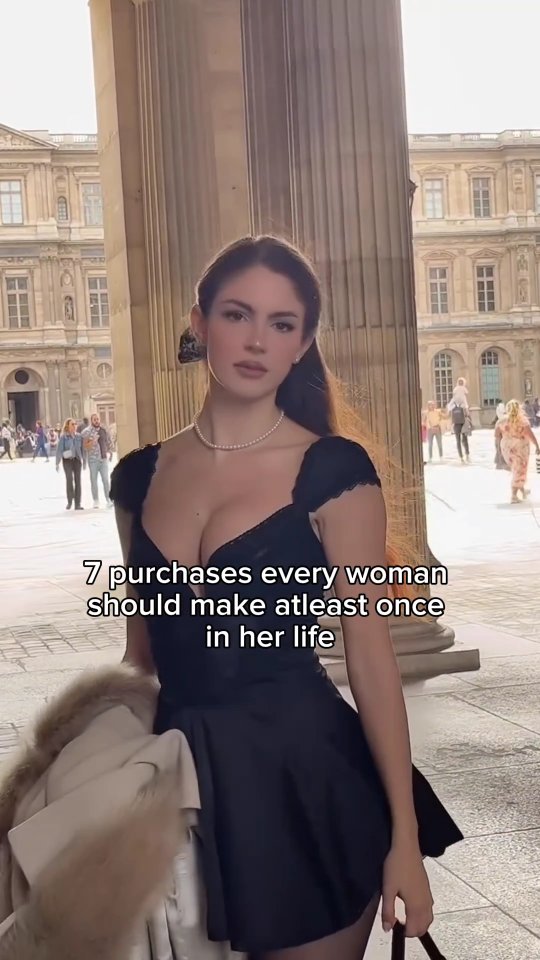 A woman stands near a building with columns, looking at the camera. She wears a black dress and a pearl necklace. Text over the image reads, '7 purchases every woman should make at least once in her life'.