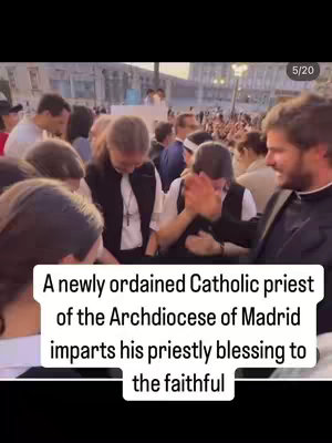 A group of people, primarily in dark attire, gather around a newly ordained Catholic priest. The priest, wearing a black vestment, is extending his hands towards a person who is bowing with their hands clasped. The background reveals what appears to be an outdoor urban setting with buildings and more individuals present. A white overlay at the bottom contains the video information.