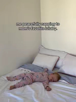 A child lies sleeping on a bed. The child is wearing pink pajamas and is positioned on top of a white and blue sheet set. The text overlay appears to be in black font.