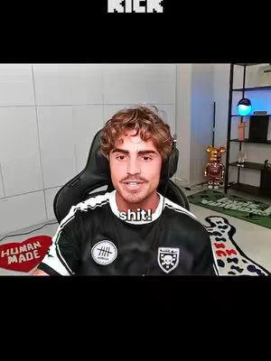 A man in a black and white jersey sits in front of a camera, speaking. The word "KICK" is written in bold letters at the top of the image. The man is in a room decorated with modern elements like a teddy bear statue and a heart-shaped 'Human Made' rug. A speech bubble overlay, “shit!,” suggests what he is saying.