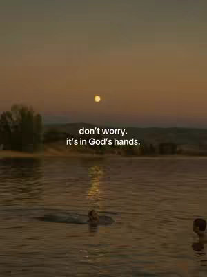 An image taken during the sunset or sunrise hours, featuring a serene body of water where a couple of figures are swimming. The sky has warm colors, with the moon in the upper portion. The text overlay reads: "don't worry. it's in God's hands."