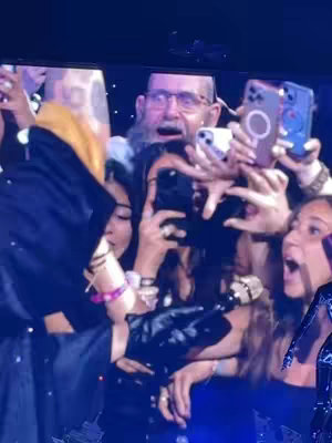 The cover image captures a close-up view of a crowd at a concert, possibly The Weeknd's performance. A group of people are holding up their phones, illuminated screens towards the stage. The composition includes both foreground and background elements, with a central focus on the audience's reaction. Colors appear to be vibrant with a mix of stage lights and phone flashes enhancing the atmosphere.