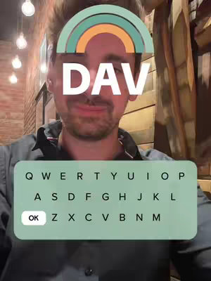 The cover image features a selfie of a man with a rainbow-colored filter over his forehead. The word "DAV" is displayed in white letters within the filter. Below his face is a mock-up keyboard graphic from a phone. The man is in a dimly lit environment, likely indoors, with exposed wooden panels and light fixtures visible.
