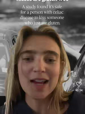 A woman with blonde hair is in a selfie video, her face is centered in the frame, she is slightly smiling and looking at the camera. Behind her, there is a car with windows and car door visible in black and white, The overlay text states a study found it's safe for a person with celiac disease to kiss someone who just ate gluten.