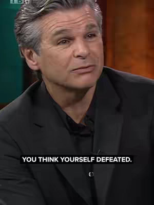 A medium shot features a man with gray hair and a dark suit. He is looking slightly to the side with a thoughtful expression. Text overlayed at the bottom of the frame says 'YOU THINK YOURSELF DEFEATED.' The background is an out-of-focus, warm-toned interior.