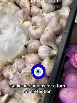 The cover image shows piles of garlic and onions inside a produce bin, suggesting a fresh produce market. In the corner, there is a pack of purplish onions. A blue circle with an eye in the center has been added to the pile. Text, also added, states "Garlic and onions for a form of protection."