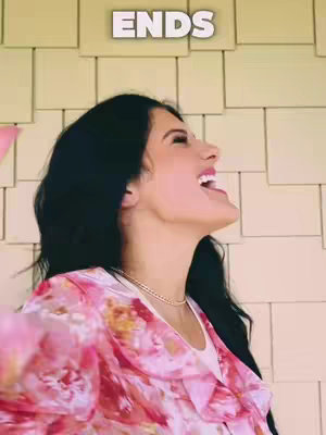 A woman with long dark hair is shown from the side, smiling and looking upwards with her mouth open. She is wearing a floral pink top and a gold necklace. Above her is a white square with the word 'ENDS' written on it. The background consists of a series of beige panels.