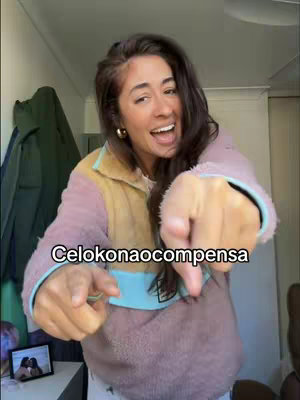 A woman with long, dark hair is pointing towards the viewer with both hands, wearing a pink and tan fleece-lined jacket. Text overlays the image, and a small framed picture is visible.