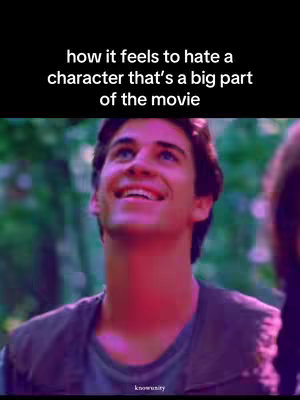 The image features a young man, possibly Liam Hemsworth, smiling upwards. The background is a blurry mix of green and purple, suggesting a natural setting. Overlayed text in a bold, white font describes how it feels to hate a movie character. Branding appears at the bottom as well.