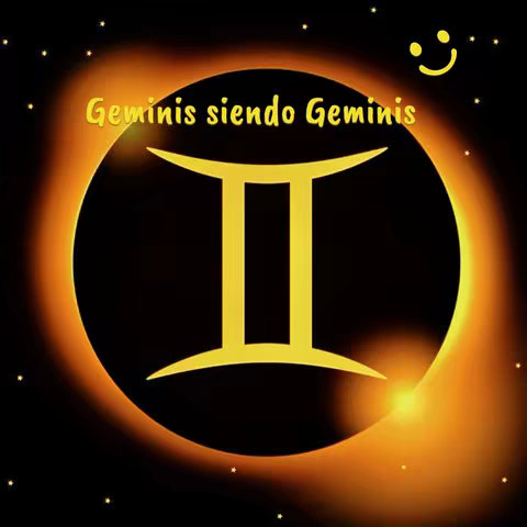 A square image with a dark background. In the center, a gold Gemini symbol is displayed inside a black circle. The circle is surrounded by a bright orange circular glow, mimicking a solar eclipse. Above and to the right, there is a yellow smiley face. Small white star-like dots are scattered around the background. Text in a yellow-orange color is placed at the top.