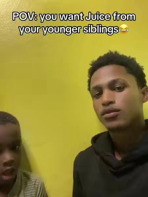 A selfie-style video with a medium shot of two young men. The background is a plain yellow wall. The man in the foreground, presumably the creator, has dark skin and is wearing a black hoodie. He is looking at the camera with a slightly concerned expression. The other person, who is partially visible on the left part of screen, appears to be his younger brother, who has a neutral expression. Text overlay at the top indicates this is a humorous take on getting juice from younger siblings.