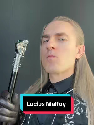 A person dressed as Lucius Malfoy from Harry Potter, holding a cane with a snake head handle. The person has long, platinum blonde hair and is looking directly at the camera. A text box at the bottom reads 'Lucius Malfoy'. The background is a solid dark gray.