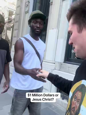 The cover image shows three men on a street. Two men are central in the frame. The man on the left is black, and the man on the right is white. The black man is wearing a tank top, and a hat. The white man is wearing a black sweater with a drawing of the face of Jesus Christ against a gold background. The white man is extending a hand to the black man as if offering to shake hands, while the man on the extreme left is standing and is looking at them. Text is overlaid at the bottom of the picture.