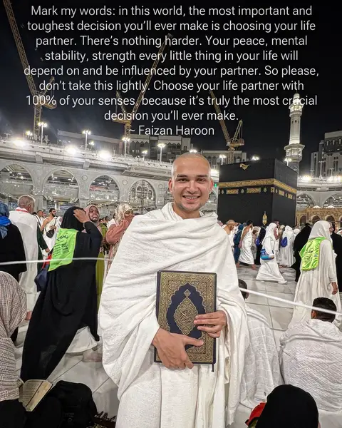 The image captures a man smiling and holding a book in front of a crowded area within a holy site. The man is dressed in white clothing, suggesting a pilgrimage. The background includes structures indicative of a religious site, with a mix of people. Text overlay is present, featuring a quote from the man.