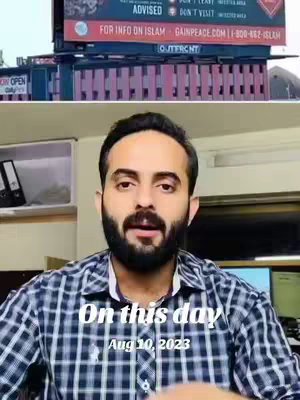 A man with a beard is in the lower half of the image, with an outdoor sign, a shelf with binders, and monitors filling the background.