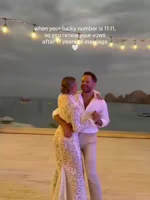 A romantic image featuring a couple embracing as they dance on a wooden platform, with a blurred background of ocean and string lights. The woman, in an elegant white gown, is cradled by the man, who is wearing a white shirt and beige pants. Text at the top reads, 'when your lucky number is 11:11, so you renew your vows after 11 years of marriage' above them.