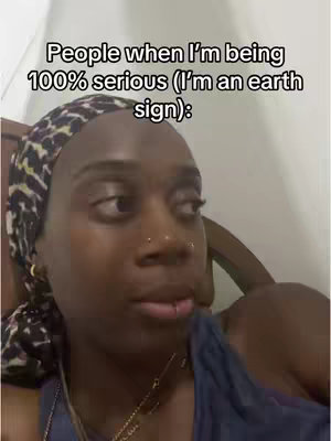 A medium shot of a dark-skinned woman looking away from the camera with a critical expression. She is wearing a headscarf with a leopard print.