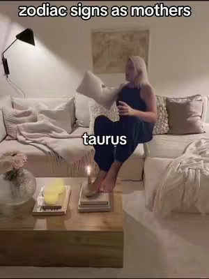 A woman sits on a white sofa in a well lit room, holding a pillow, and a text overlay says 'taurus'.