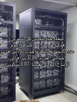 The image shows large black server racks densely filled with circuit boards and hardware, set against a plain, light-colored background. Text in Arabic is overlaid on the image, providing details about the equipment.