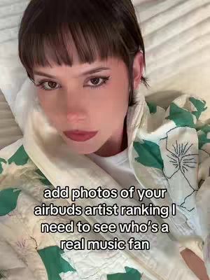 A selfie-style shot features a woman in bed, looking towards the camera with slightly parted lips. Her dark hair is cut into a bob, and a patterned jacket covers her over a white T-shirt. Text is overlaid at the bottom.